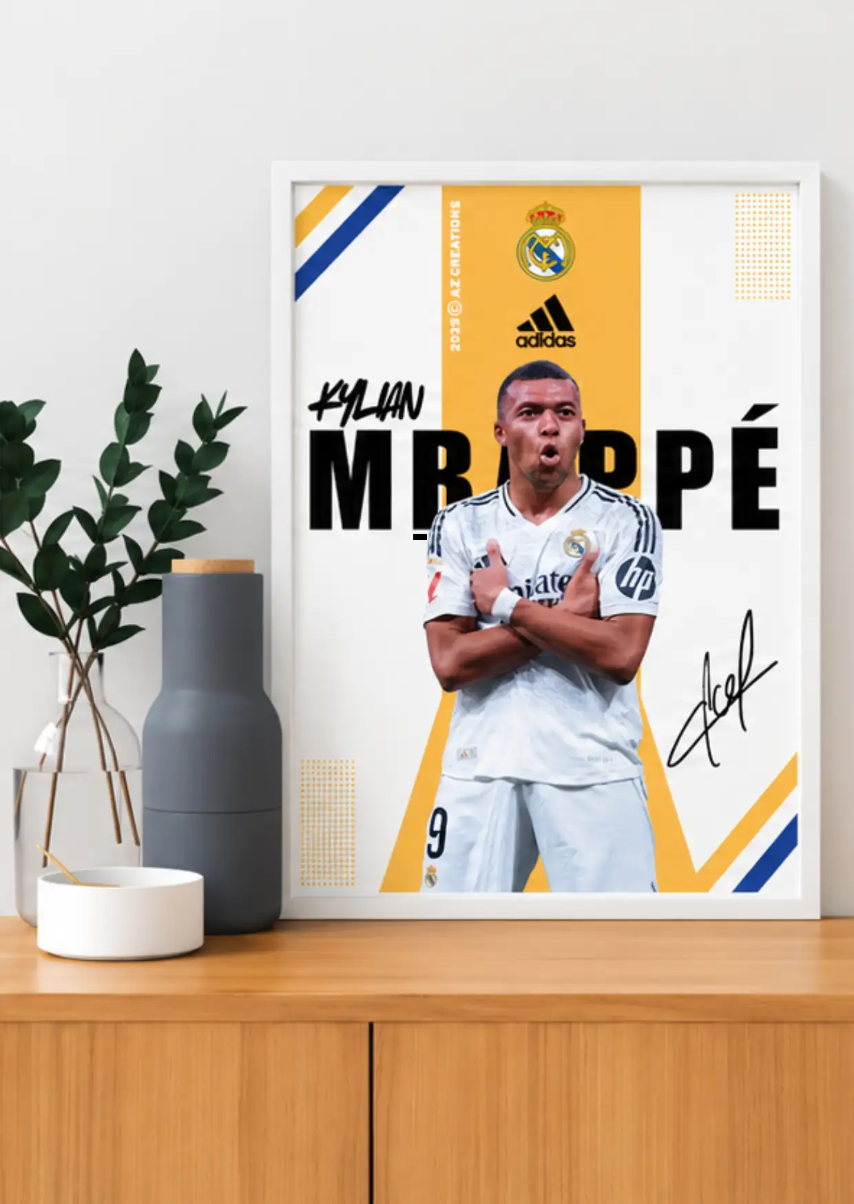 White-framed Kylian Mbappé Real Madrid poster showing his crossed-arm pose in a white number 9 kit against yellow graphics.